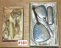 Two vintage dresser sets displayed side by side in their original boxes with satin lining. The adult set on the right has a bright silver reflective finish on brush and mirrors.