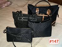 Four black jacquard monogram handbags arranged on surface