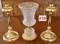 Full view of the brass candlesticks and crystal vase set arranged on a wooden table, showing three-piece garniture.