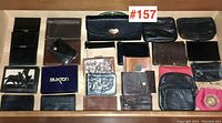 Top view of all leather wallets and key cases arranged in rows on a wooden surface with lot number #157.