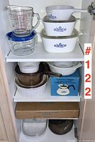Top shelf showing Pyrex measuring cup, plastic lidded bowl, and three nested Blue Cornflower CorningWare pieces