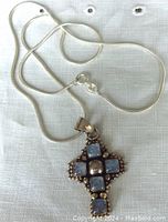 Full view of sterling silver snake chain with rainbow moonstone pendant laid on fabric background.