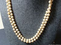 Photo of the single strand pearl necklace displayed on a grey fabric bust stand showing pearl size and luster.