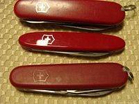 Top closed view showing three red Victorinox Swiss Army knives with shield logos.
