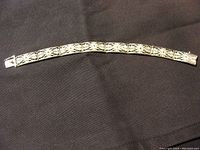 Full view of the vintage Birks filigree sterling silver bracelet stretched out on black fabric.