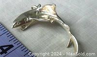 Close-up photo of the silver shark pendant showing side profile with open mouth, fins, and realistic body shape beside a ruler for size reference.