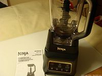 Ninja BC701CC0 Professional Plus Blender with instructions showing the brand, model, and control panel on base with clear blending jar.
