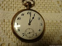 Front view of the pocket watch showing white enamel double sunk dial with black Arabic numerals and subsidiary seconds dial.