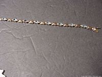 Full view of bracelet showing length and linked design with light blue rhinestones set in gold over silver.