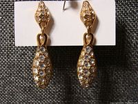 Front view of Swarovski gold-tone dangle earrings with clear crystals on card.
