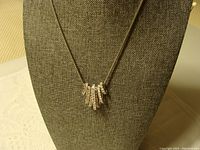 Full view of the necklace displayed on a bust stand showing the silver chain and multiple vertical bar pendants with clear rhinestones.