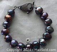 Full view of bracelet showing the dark peacock colored baroque freshwater pearls and the textured dark toggle clasp.