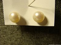Clear close-up of the pearl stud earrings on a white backing, highlighting pearl size and luster.