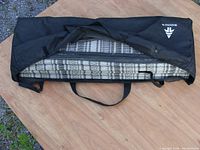 Carpet folded inside black carrying case with Wood's brand name visible, showing straps and fabric texture.