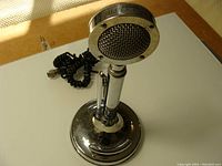 Front view of vintage Astatic Silver Eagle microphone with chrome base and coiled cable.