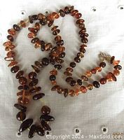 Full shot of the vintage amber chip bead necklace laid out on a linen cloth, showing the range of bead sizes and colors.