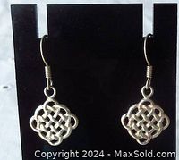 Front view of pair of vintage sterling silver Celtic knot earrings on black stand.