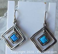 Front view of pair of vintage silver drop earrings with blue opal stones in square hammered frames.