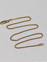 Full view of the gold anklet laid flat showing length and clasp.