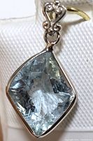 Close-up of light blue faceted aquamarine gemstone set in 14K gold pendant with decorative bail.