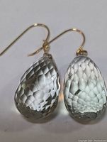 Close-up photo of one earring showing faceted green amethyst teardrop and thin 14K gold hook