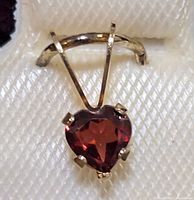 Close-up image of heart-shaped garnet pendant in yellow gold setting.