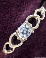 Close-up image of the yellow gold band featuring open heart shapes with a central round-cut diamond.