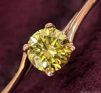 Front-angle view of round yellow diamond set in 10K rose gold four-prong setting