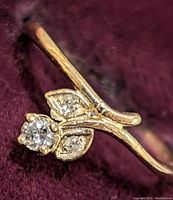 Close-up photo of the 10K gold diamond ring showcasing the central diamond and leaf-shaped diamond accents on a purple velvet background.