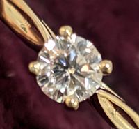 Close-up of the round-cut lab diamond set in 10K yellow gold with four prongs.