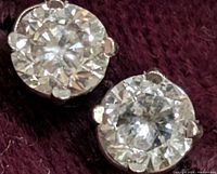 Front view of both round diamonds in four-prong settings on dark background