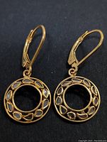 Front view of gold-tone sterling silver circular earrings with diamond accents and lever-back clasp.