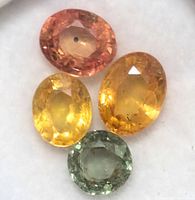 Four loose oval sapphires of different colors on white background