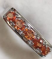 Close-up photo of the sterling silver band with orange sapphire oval stones.