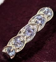 Close-up angled top view of the sterling silver ring showing the row of tanzanite gemstones.