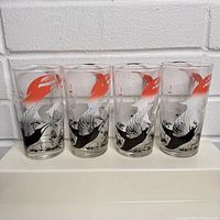 Four vintage bar glasses, each with a colorful flying wild geese design in black, white, and red/orange on clear glass.
