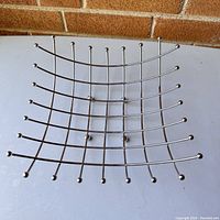 Top view of modern chrome metal fruit basket shown on flat surface to display size and grid pattern.