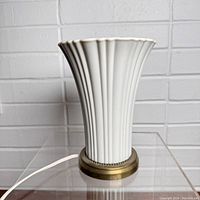 Photo showing the full dresser up light lamp with ridged fluted design, cream color, brass base, and attached power cord.