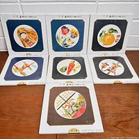 Seven vintage Japanese Chigari paper art craft kit boxes in original sealed packaging, each showing different circular artwork through a window on the front, depicting traditional Japanese and nature scenes.