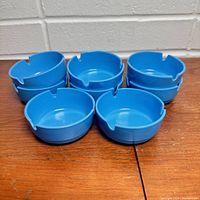 Stack of eight vintage blue melamine mini ashtrays showing round shape and cigarette rests.