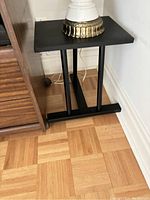 Black metal plant stand placed next to furniture with a decorative lamp on top