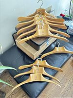 Set of 10 vintage heavy wooden coat and suit hangers from Fratelli Reguiti, showing natural wood finish, metal hooks, and brand marking on each hanger
