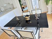 Table and four chairs assembled in room with parquet floor and kitchen background