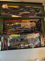 Top view of vintage green Union Chest toolbox filled with various hand tools such as pliers, wrenches, screwdrivers, files, and other small parts.