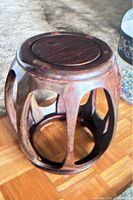 Full view of the vintage barrel-shaped garden stool in rosewood showing wood grain and open carved sides.