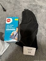 Photo of new Life brand arm sling in its original blue box alongside a used black arm sling with ring attachment.