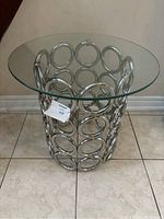 Front side view of chrome side table showing circular open ring pattern and clear glass top.