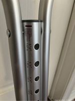 Close-up of silver aluminum crutch showing height adjustment holes marked 5'2" to 5'10" and metric equivalents.