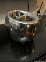 Silver metal vase with rounded shape on black surface