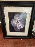 Full view of framed flower wall art featuring purple roses and dark frame with gold inner edge